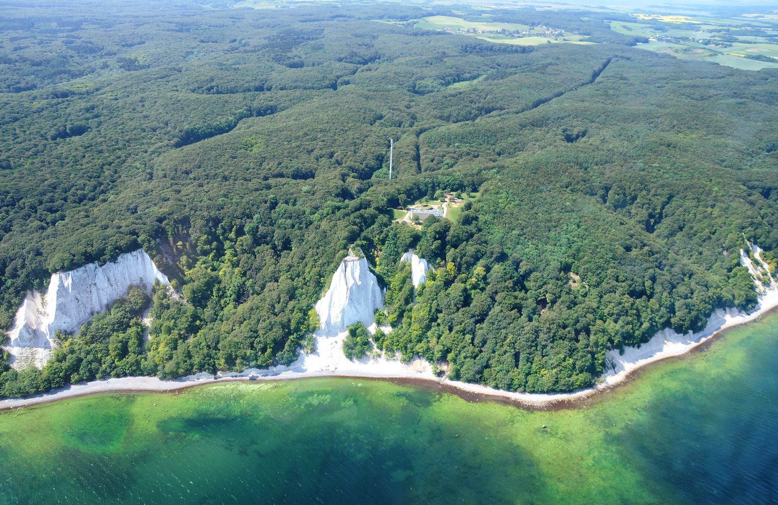 Luftbild der Kreideküste im Nationalpark Jasmund: weiße Kreidefelsen zwischen dichtem Buchenwald und türkisfarbenem Wasser