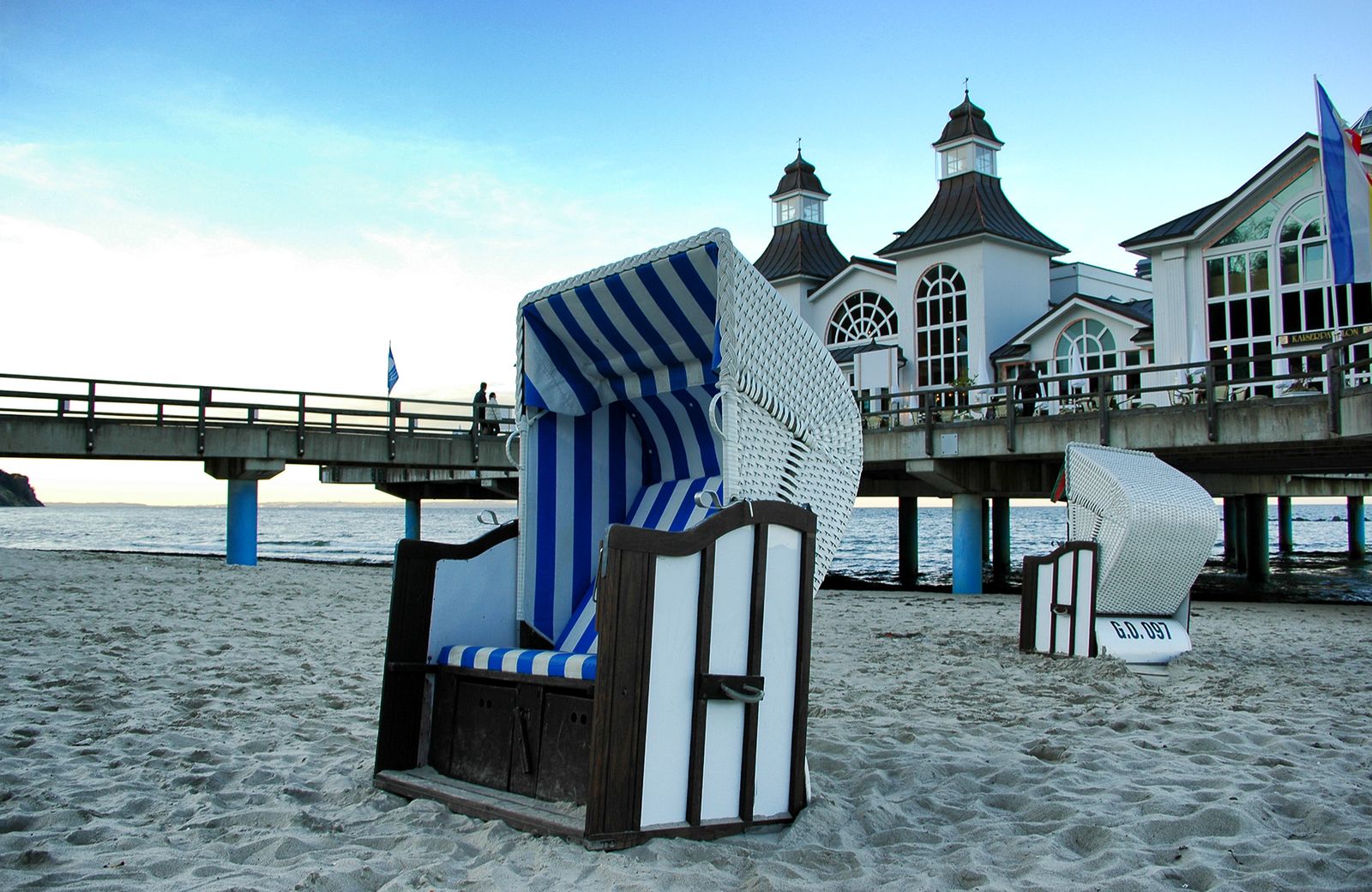 Blau-weiß gestreifter Strandkorb am Strand von Sellin, dahinter das Brückenhaus der Seebrücke